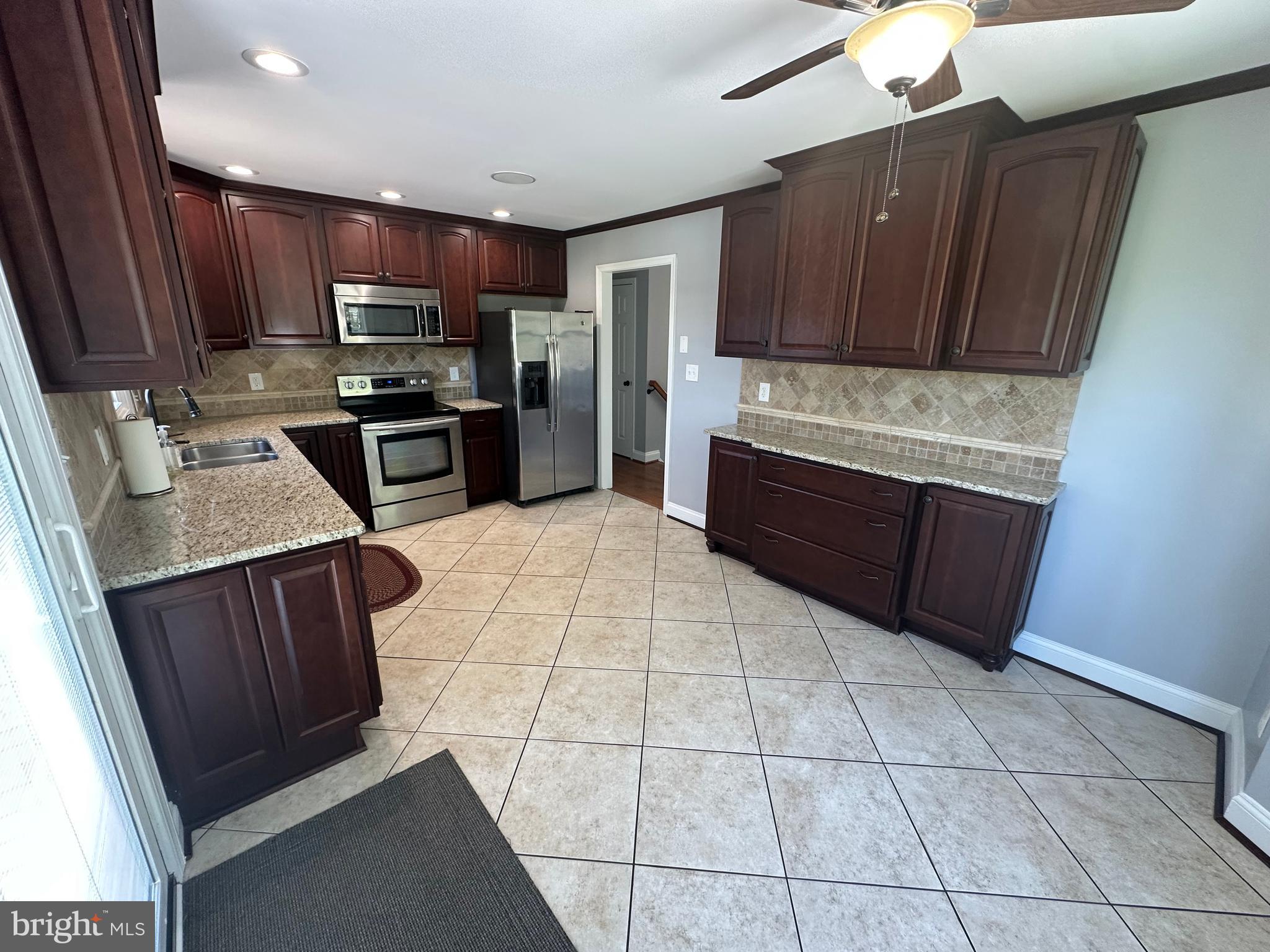 3457 Baker Road Westminster, MD 21157 - Photo 23 of 105 a large kitchen with granite countertop a stove a microwave oven a sink dishwasher and wooden cabinets