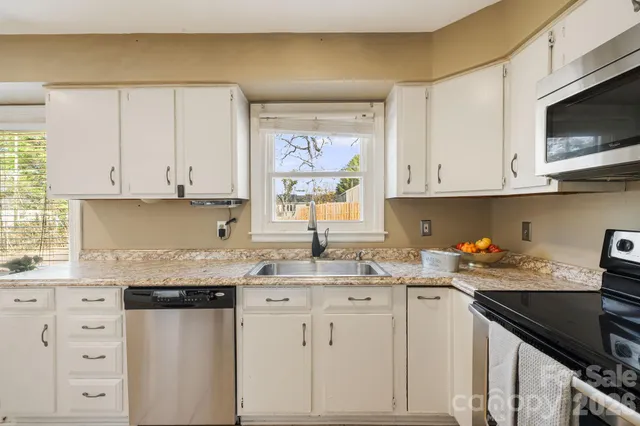 a kitchen with stainless steel appliances granite countertop a sink a stove and cabinets