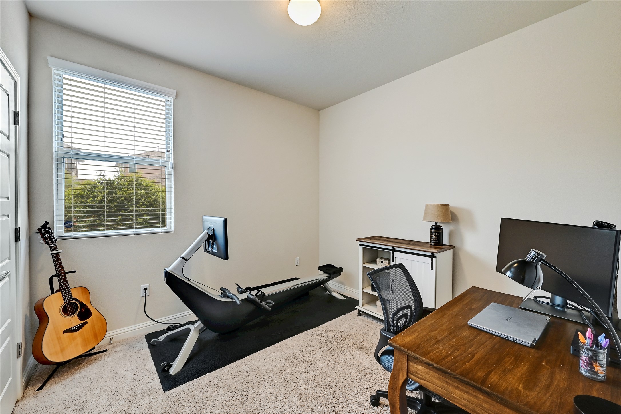 6814 East Riverside Drive, Unit 64 Austin, TX 78741 - Photo 14 of 17 Additional bedroom located on the 1st floor can be used as office space or as a bedroom. A well-lit versatile space features a window with blinds, soft carpet flooring, and a modern ceiling fixture.