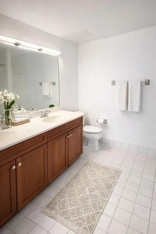 a spacious bathroom with a granite countertop sink toilet and mirror