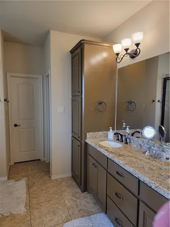 a bathroom with a granite countertop sink a light fixture and a mirror