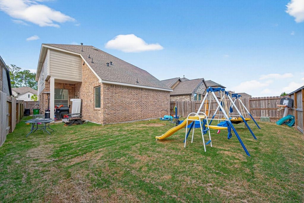 12154 Texas Trumpet Trail Humble, TX 77346 - Photo 20 of 21 a view of a backyard with a slide and a child swing