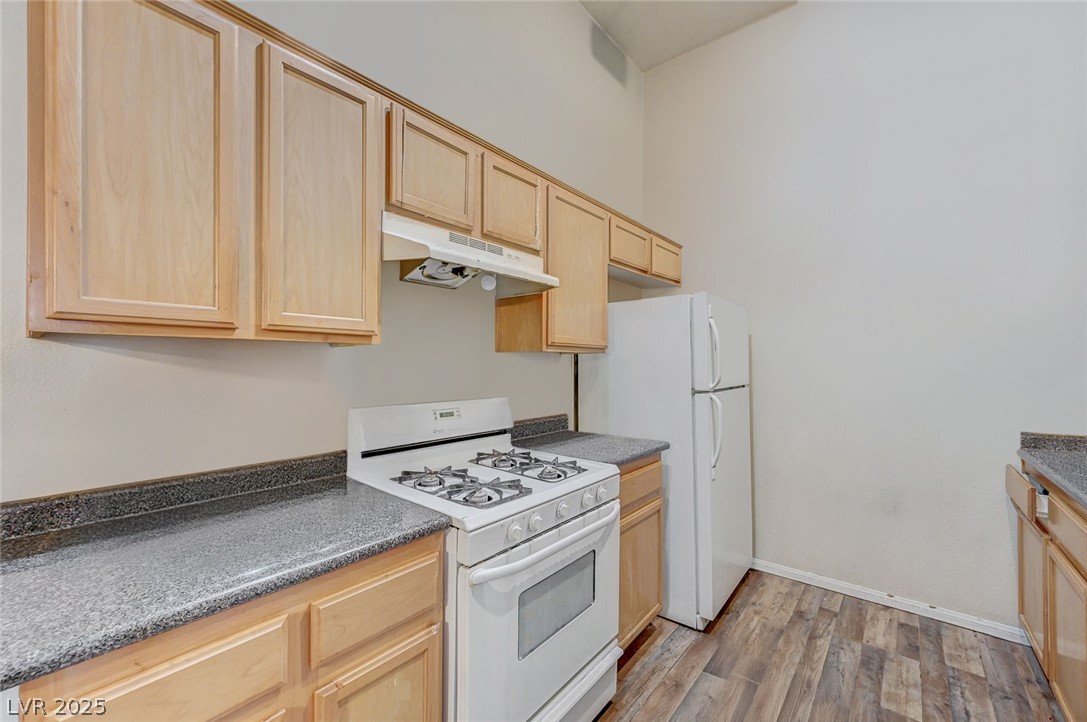 2305 West Horizon Ridge Parkway, Unit 1223 Henderson, NV 89052 - Photo 12 of 28 Kitchen with light wood finish cabinetry, white appliances, and dark wood-type flooring