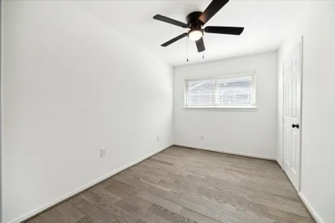 a view of empty room with wooden floor and ceiling fan