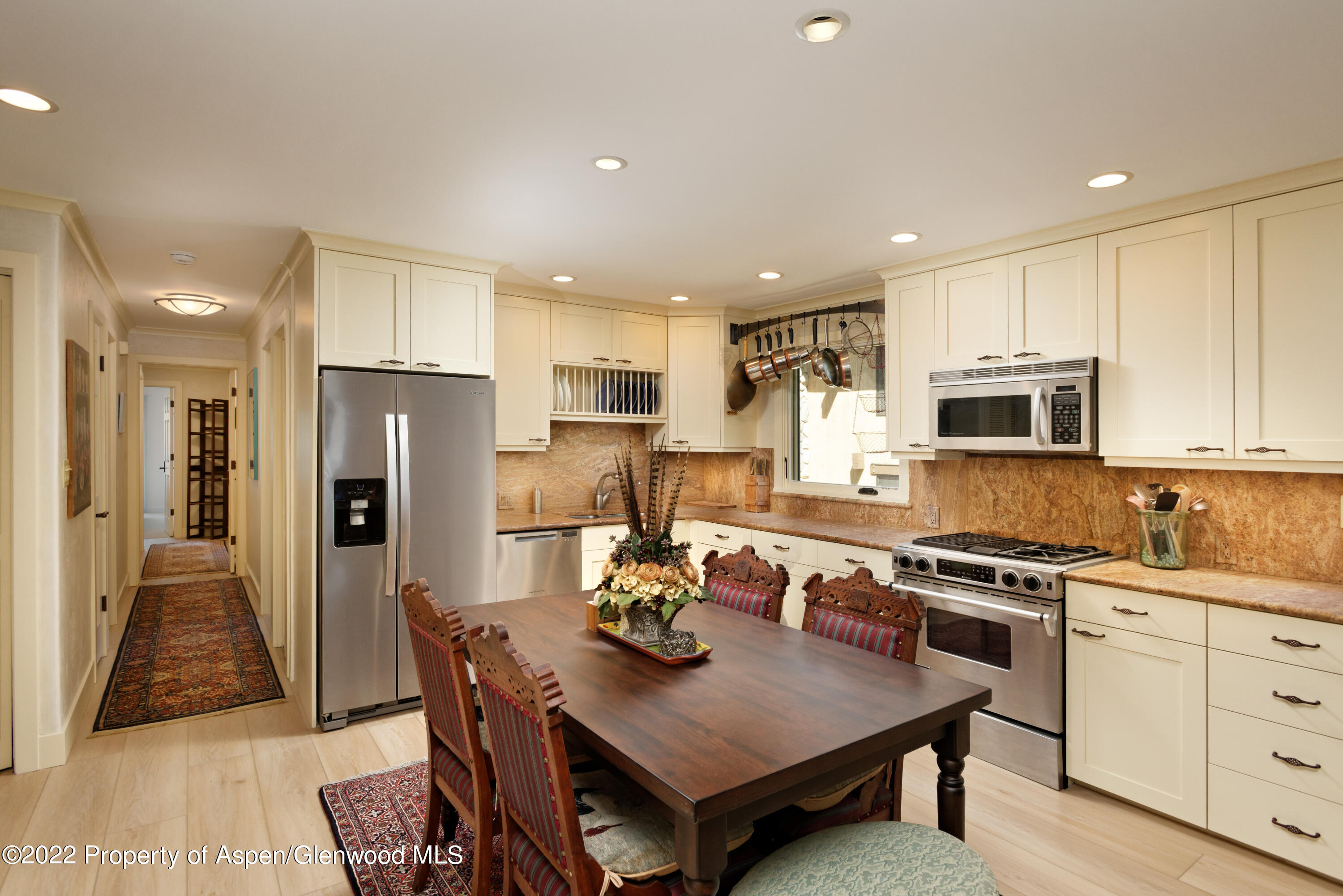 a kitchen with stainless steel appliances granite countertop a kitchen island hardwood floor a dining table and chairs