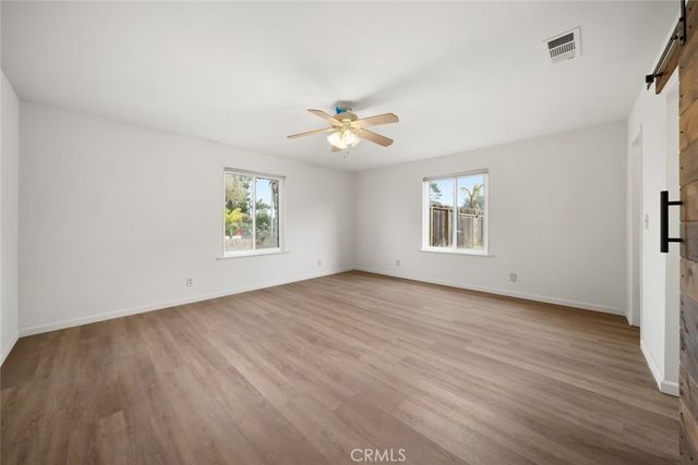 an empty room with windows and a ceiling fan
