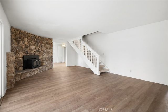 a view of an empty room with wooden floor and a fireplace
