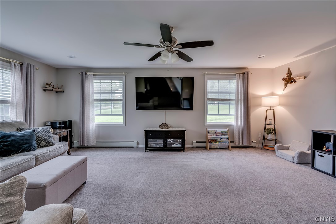 A spacious recreation room features wall-to-wall carpeting and symmetrical windows overlooking the yard.