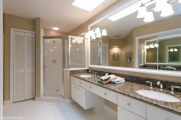 a bathroom with double vanity sinks a vanity a lamp and a mirror