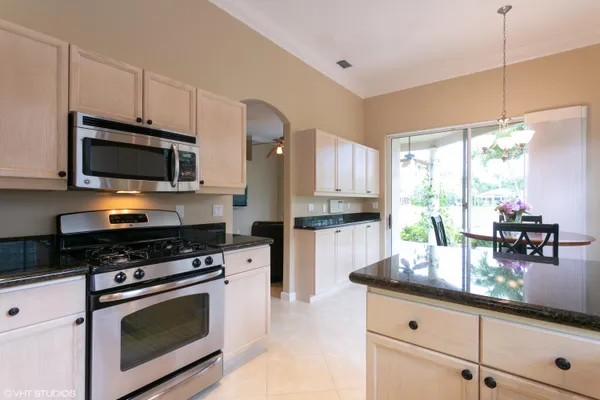 a kitchen with granite countertop a stove a sink and a microwave