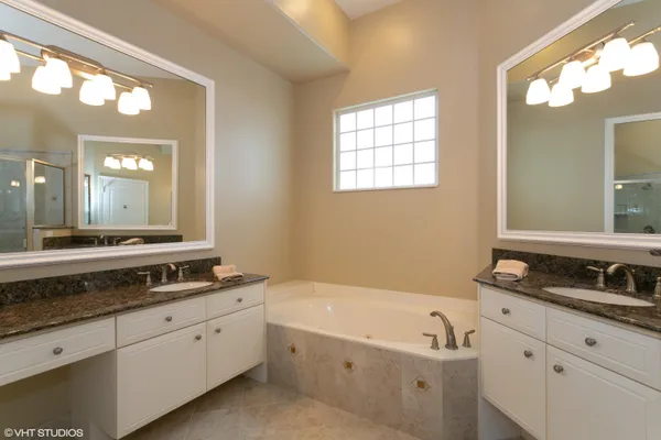 a bathroom with a granite countertop tub a double vanity sink and mirror