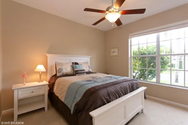 a bedroom with a large bed and a chandelier fan