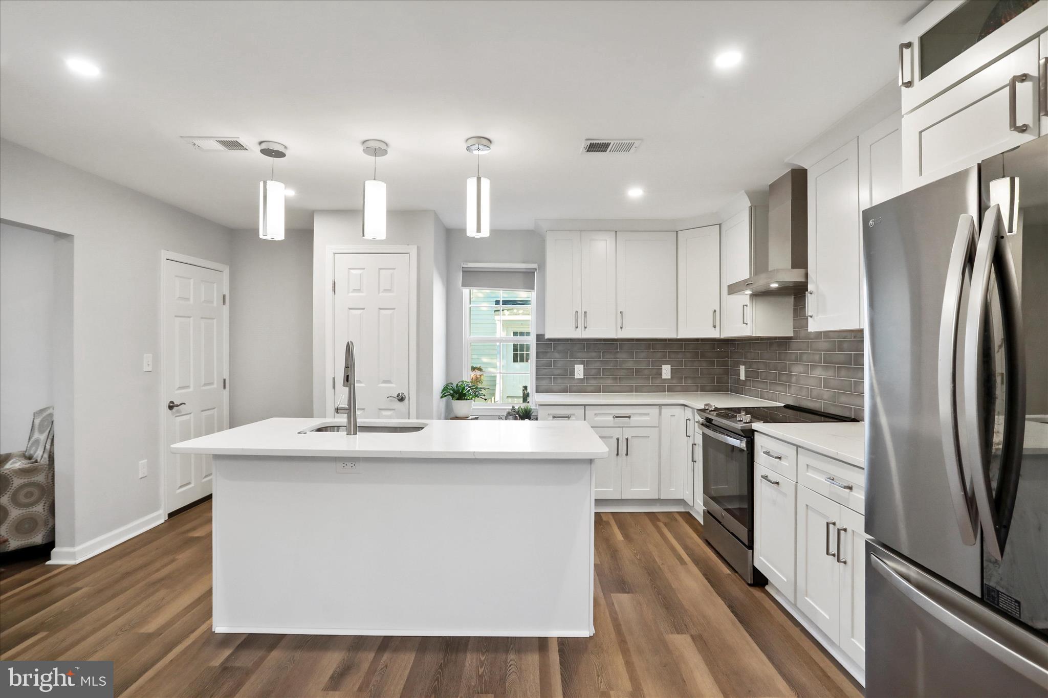 408 Blue Ridge Avenue Northeast Leesburg, VA 20176 - Photo 19 of 36 a large kitchen with stainless steel appliances kitchen island granite countertop a stove a sink a refrigerator and white cabinets with wooden floor