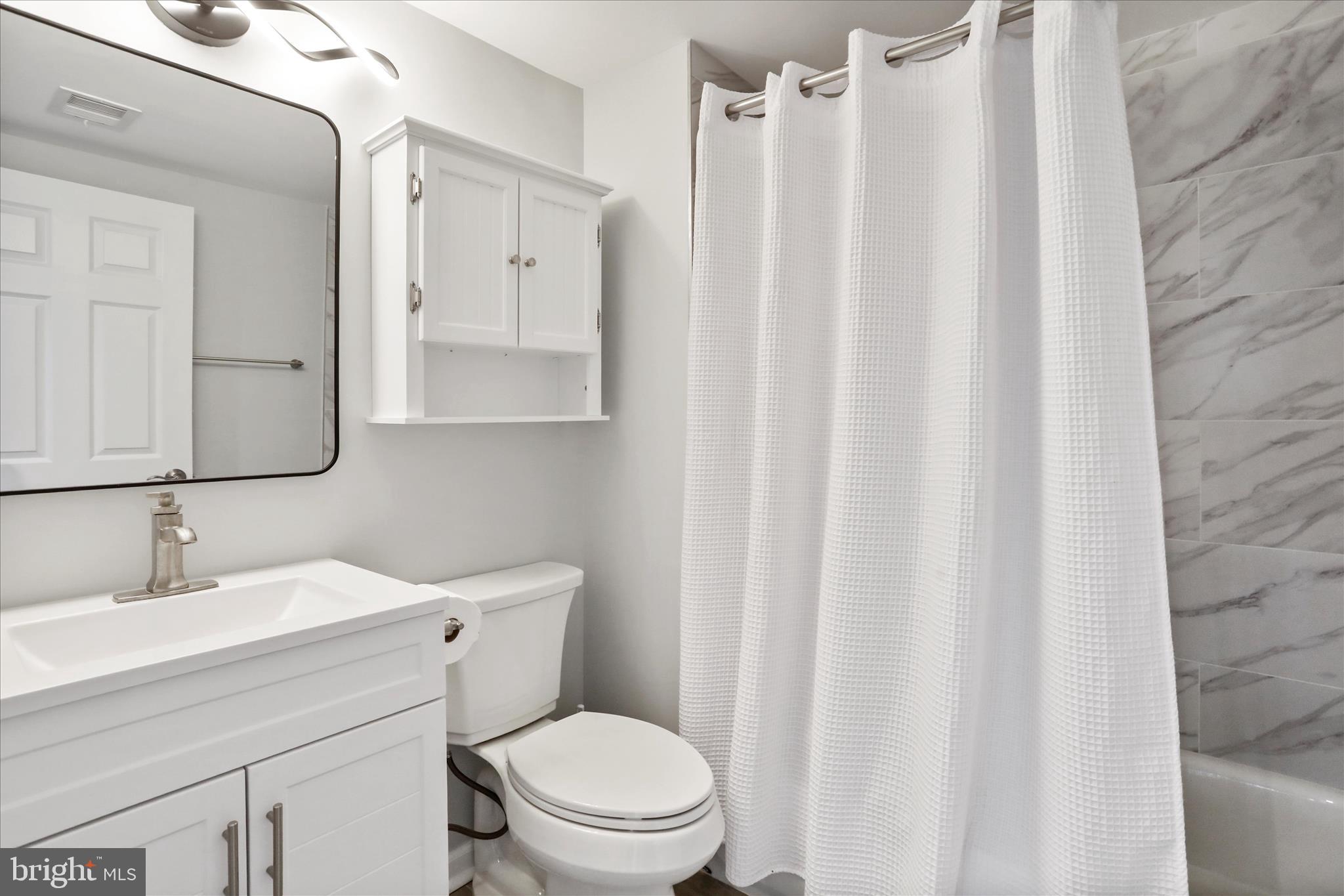 408 Blue Ridge Avenue Northeast Leesburg, VA 20176 - Photo 33 of 36 a bathroom with a sink a toilet and shower curtain