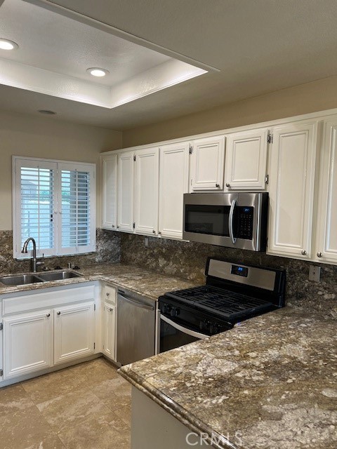 31 Chandon Laguna Niguel, CA 92677 - Photo 3 of 13 a kitchen with stainless steel appliances granite countertop a stove a sink a microwave and white cabinets