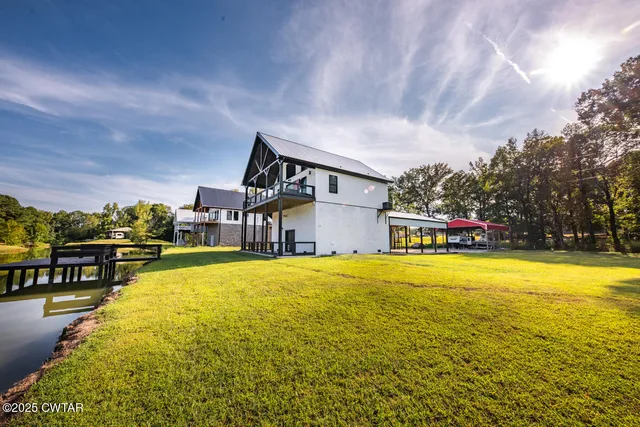 a view of a big house with a small yard and large trees