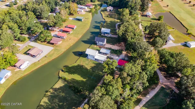 an aerial view of a house with swimming pool and large trees