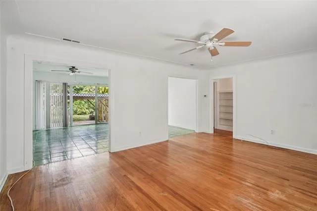 a view of an empty room with wooden floor and a window