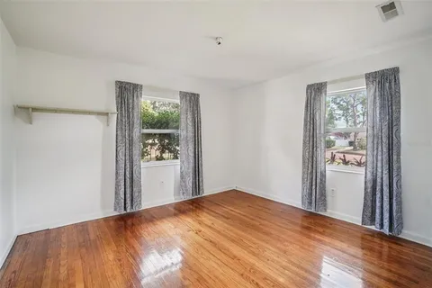 a bedroom with wooden floor and a window
