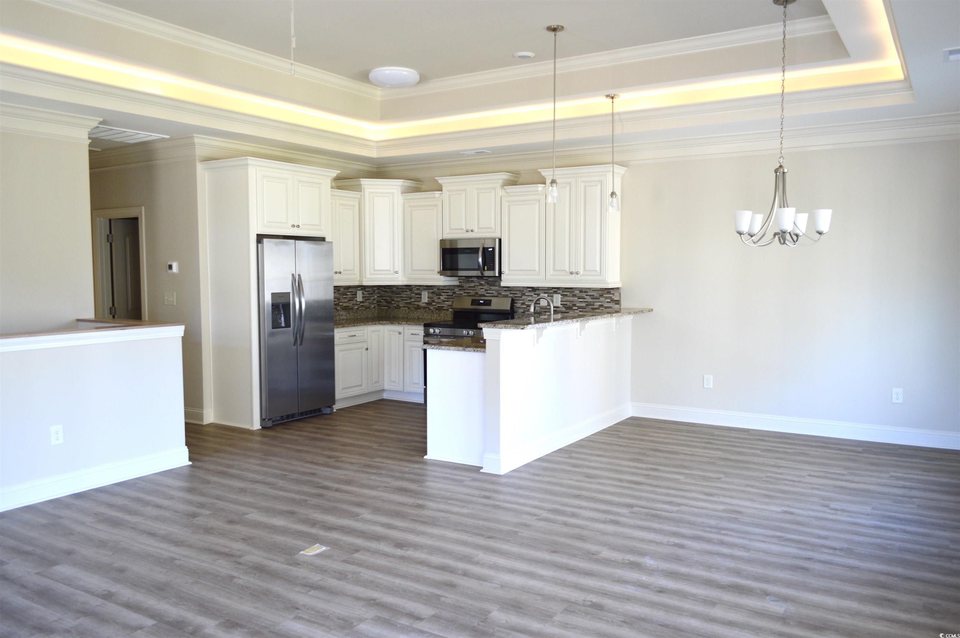 108 Hallandale Lane, Unit RIGHT Murrells Inlet, SC 29576 - Photo 6 of 35 Kitchen featuring kitchen peninsula, appliances with stainless steel finishes, a tray ceiling, decorative light fixtures, and off white cabinetry
