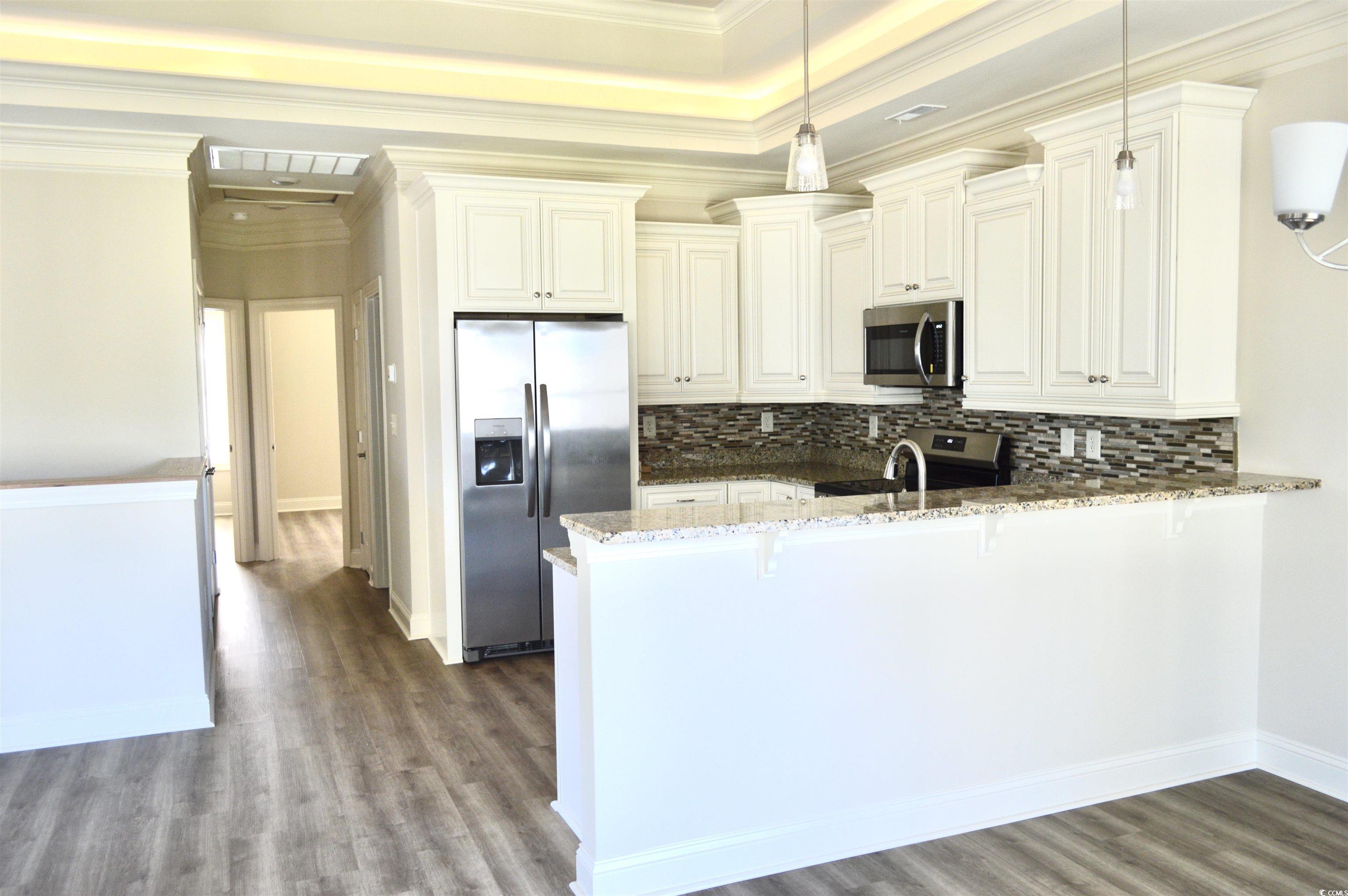 108 Hallandale Lane, Unit RIGHT Murrells Inlet, SC 29576 - Photo 7 of 35 Kitchen featuring hanging light fixtures, tasteful backsplash, kitchen peninsula, dark stone counters, and appliances with stainless steel finishes