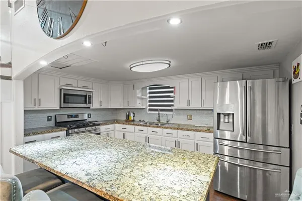 a kitchen with stainless steel appliances granite countertop a sink refrigerator and cabinets