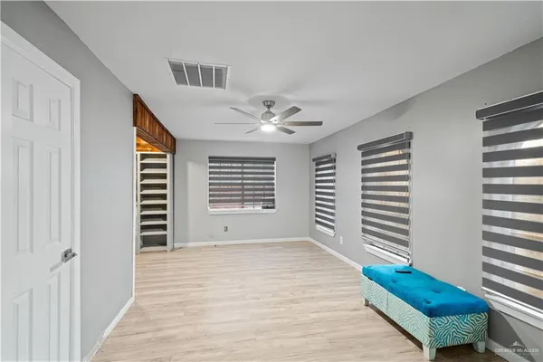 a view of an empty room with a window and hardwood floor