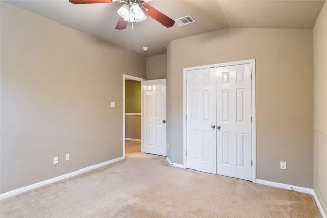 an empty room with chandelier fan and closet area