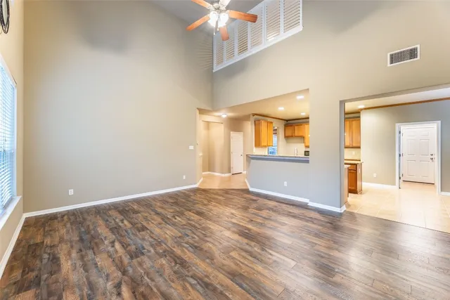 a view of a big room with wooden floor and a kitchen