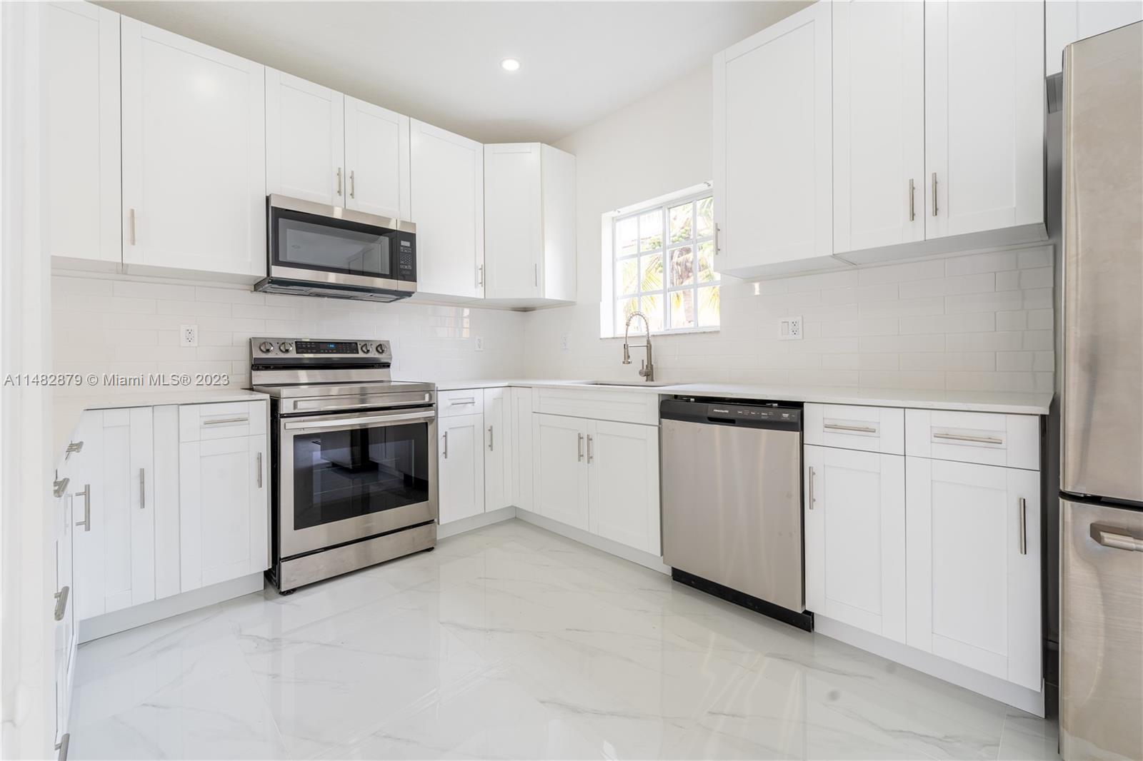 14346 Southwest 134th Place Miami, FL 33186 - Photo 5 of 36 a kitchen with white cabinets and white appliances