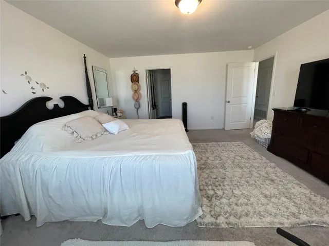 a spacious bedroom with a bed and a flat screen tv