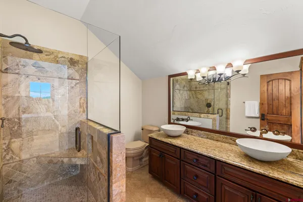 a bathroom with a granite countertop sink a mirror and a shower