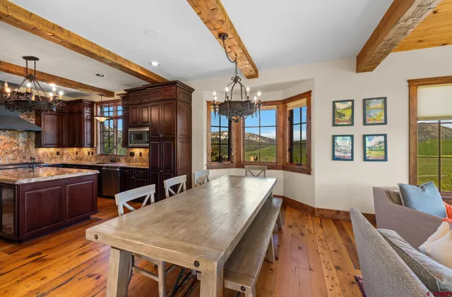 a dining hall with stainless steel appliances granite countertop a sink dishwasher and a black countertops with wooden floor