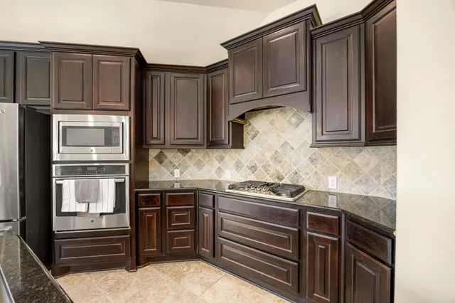 a kitchen with stainless steel appliances granite countertop wooden cabinets and a stove top oven