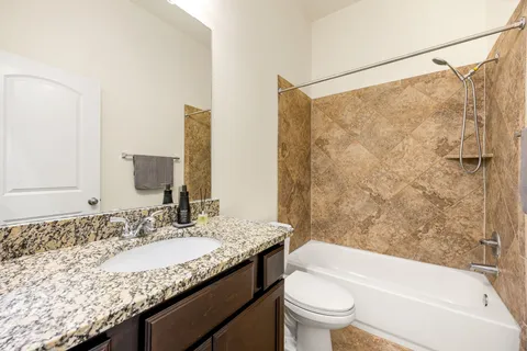 a bathroom with a granite countertop sink a toilet and shower