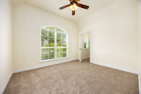 an empty room with a window and a fan
