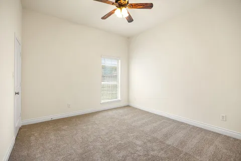 an empty room with a ceiling fan and carpet
