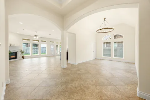 a view of an empty room with kitchen and a window
