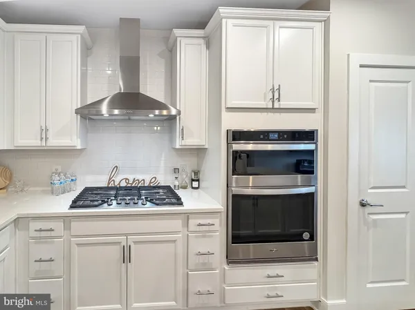 a large kitchen with kitchen island a stove a sink a refrigerator and a refrigerator with wooden floor