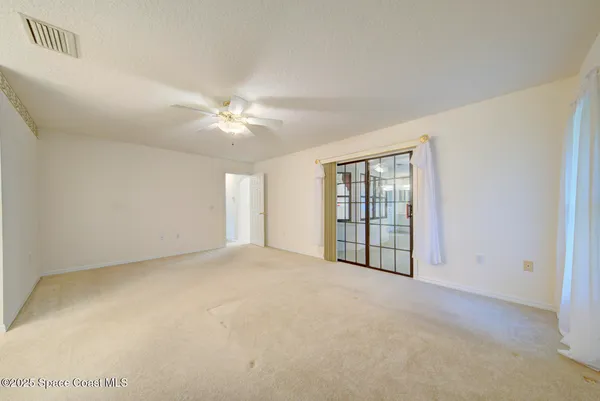 an empty room with windows and fan