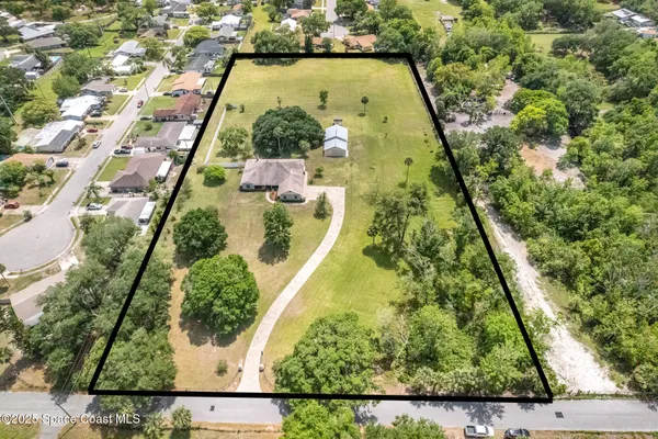 a view of a house with a big yard and large tree