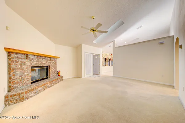 an empty room with chandelier fan and windows