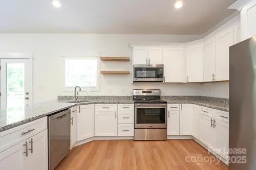 a kitchen with stainless steel appliances granite countertop a stove a sink and a microwave