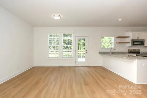 a view of a kitchen with wooden floor and a window