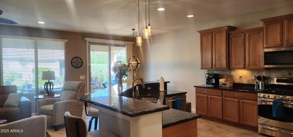 a kitchen with stainless steel appliances granite countertop a stove a sink dishwasher a microwave oven and a dining table with wooden floor