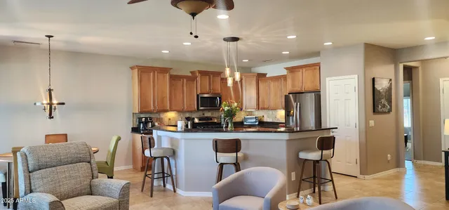 a view of kitchen with kitchen island stainless steel appliances refrigerator stove dining table and chairs