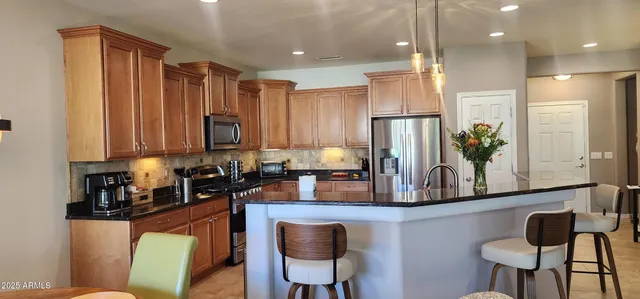 a kitchen with stainless steel appliances granite countertop sink refrigerator dining table and chairs