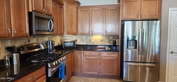 a kitchen with granite countertop a refrigerator stove and cabinets