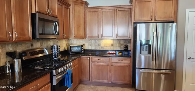 a kitchen with granite countertop a refrigerator stove and cabinets