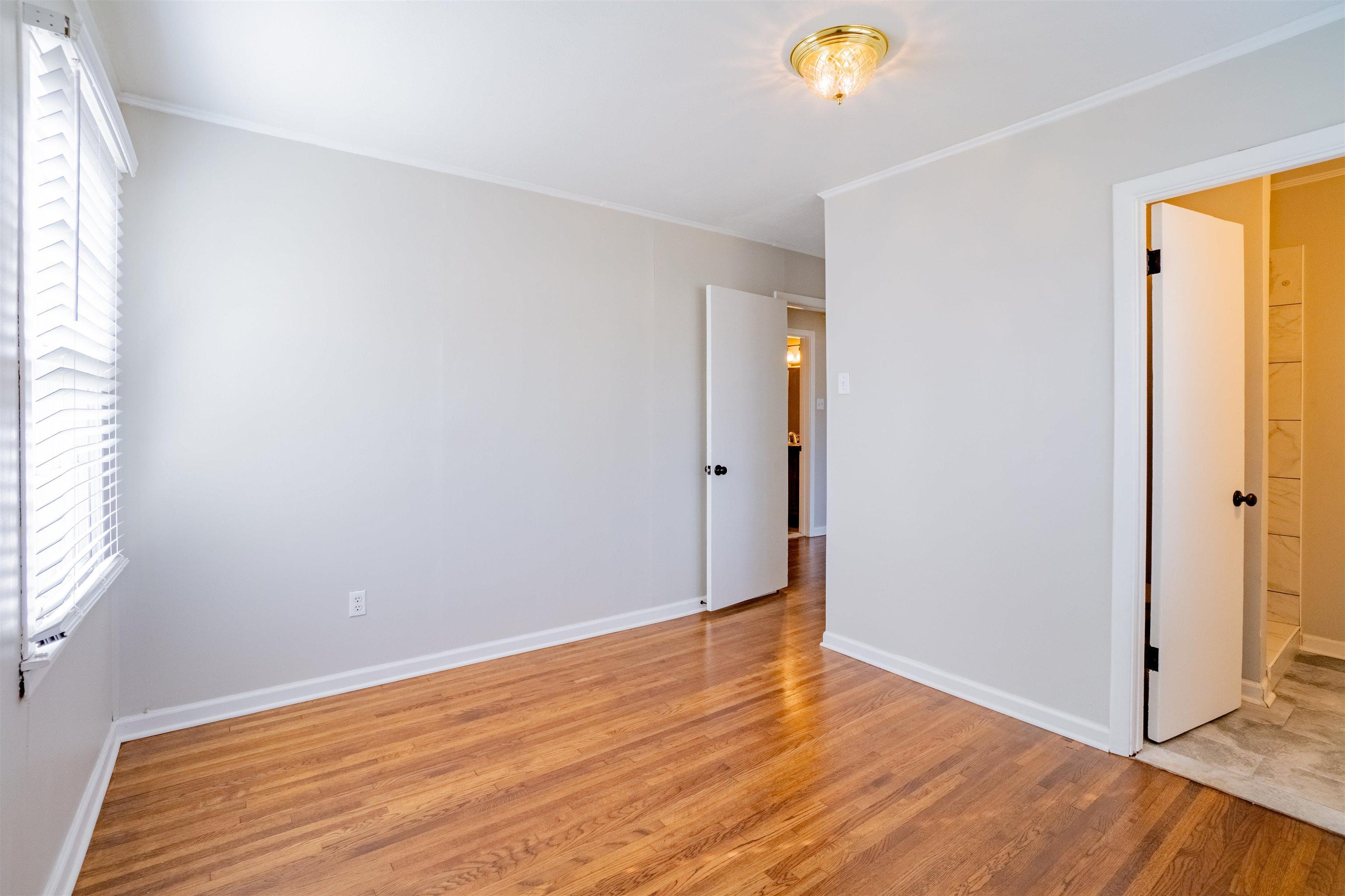 1349 Colonial Road Memphis, TN 38117 - Photo 18 of 29 a view of an empty room with wooden floor and a window